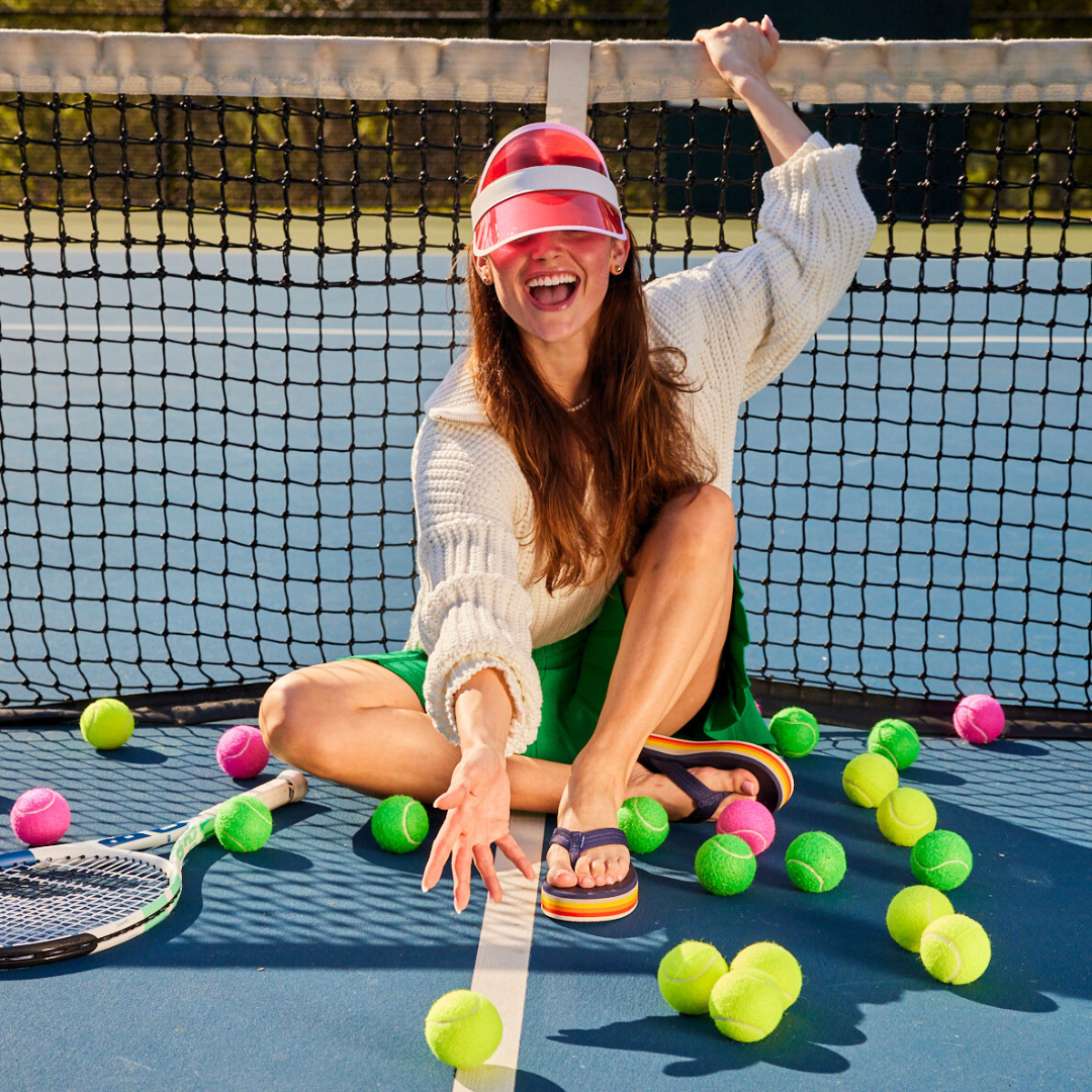 woman on tennis court surrounded by tennis balls and wearing Dunes Sunset platform sandals for women
