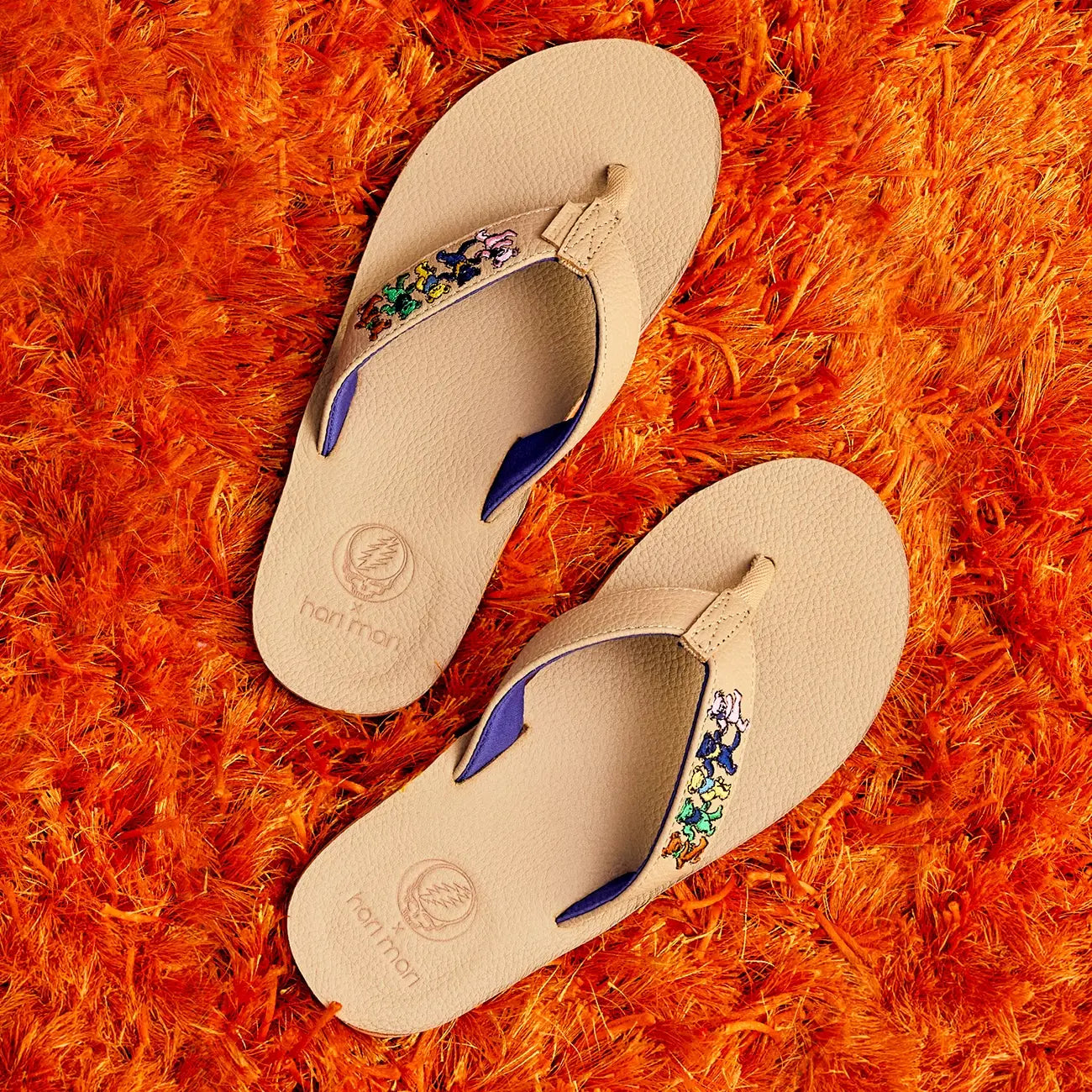 Grateful Dead x Hari Mari flip-flops with decorative straps on an orange shag rug