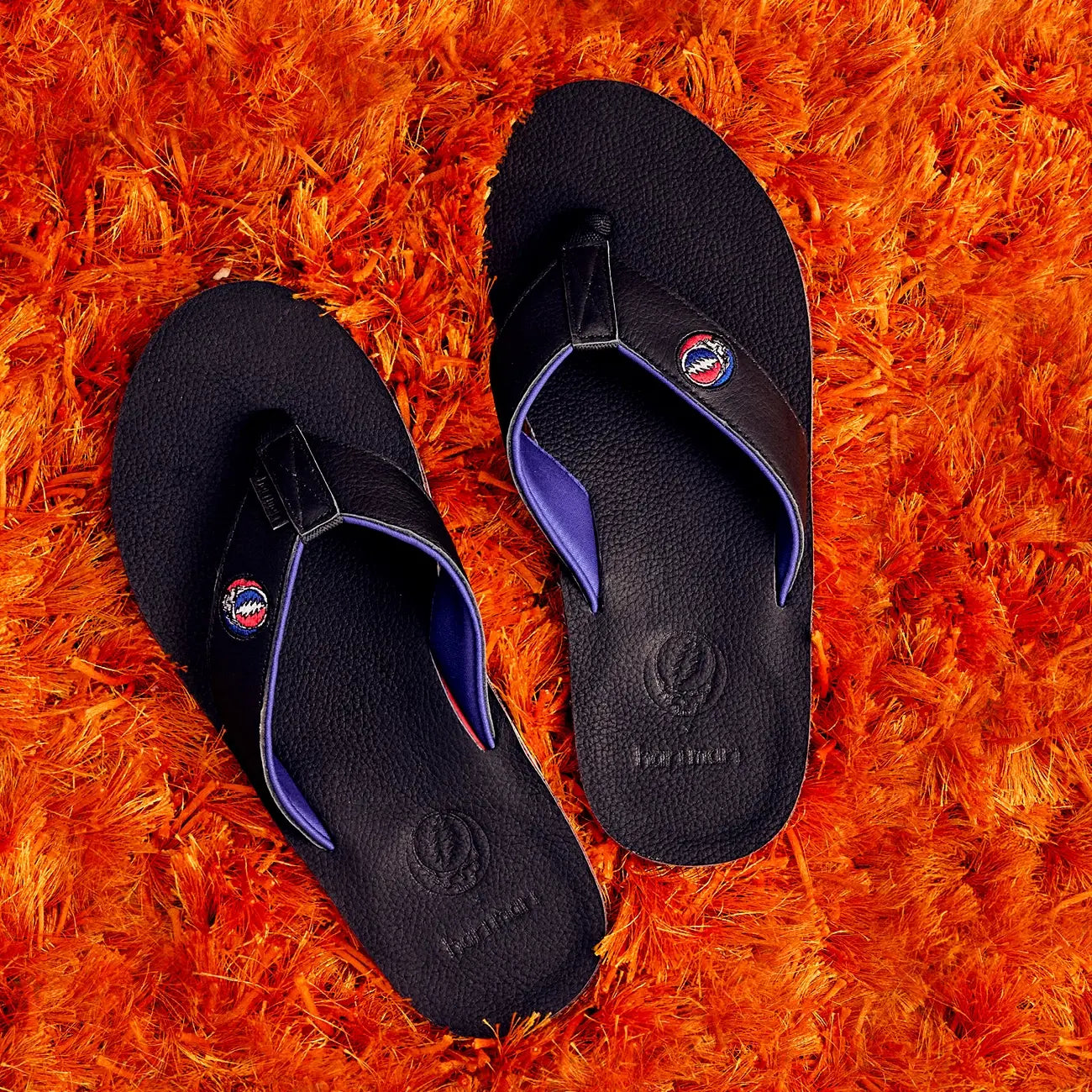 Grateful Dead x Hari Mari men's flip-flops on an orange shag rug
