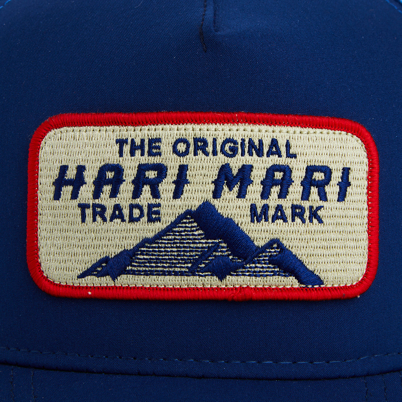 Blue trucker hat from Hari Mari with logo patch shown close up