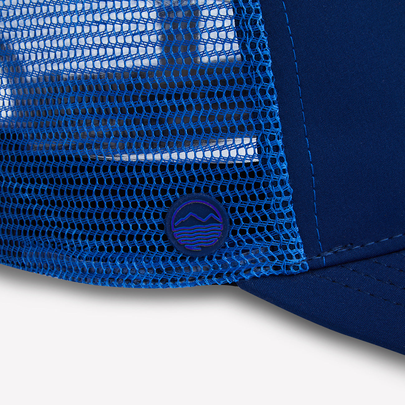 Close-up of a Hari Mari navy trucker hat with a brand logo