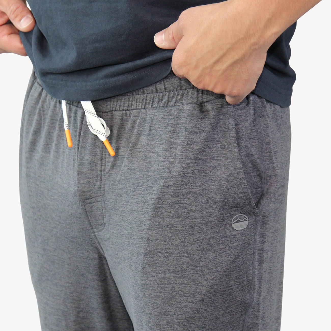 Close-up of heather gray joggers for men showing the drawstring and Hari Mari logo on the left hip.