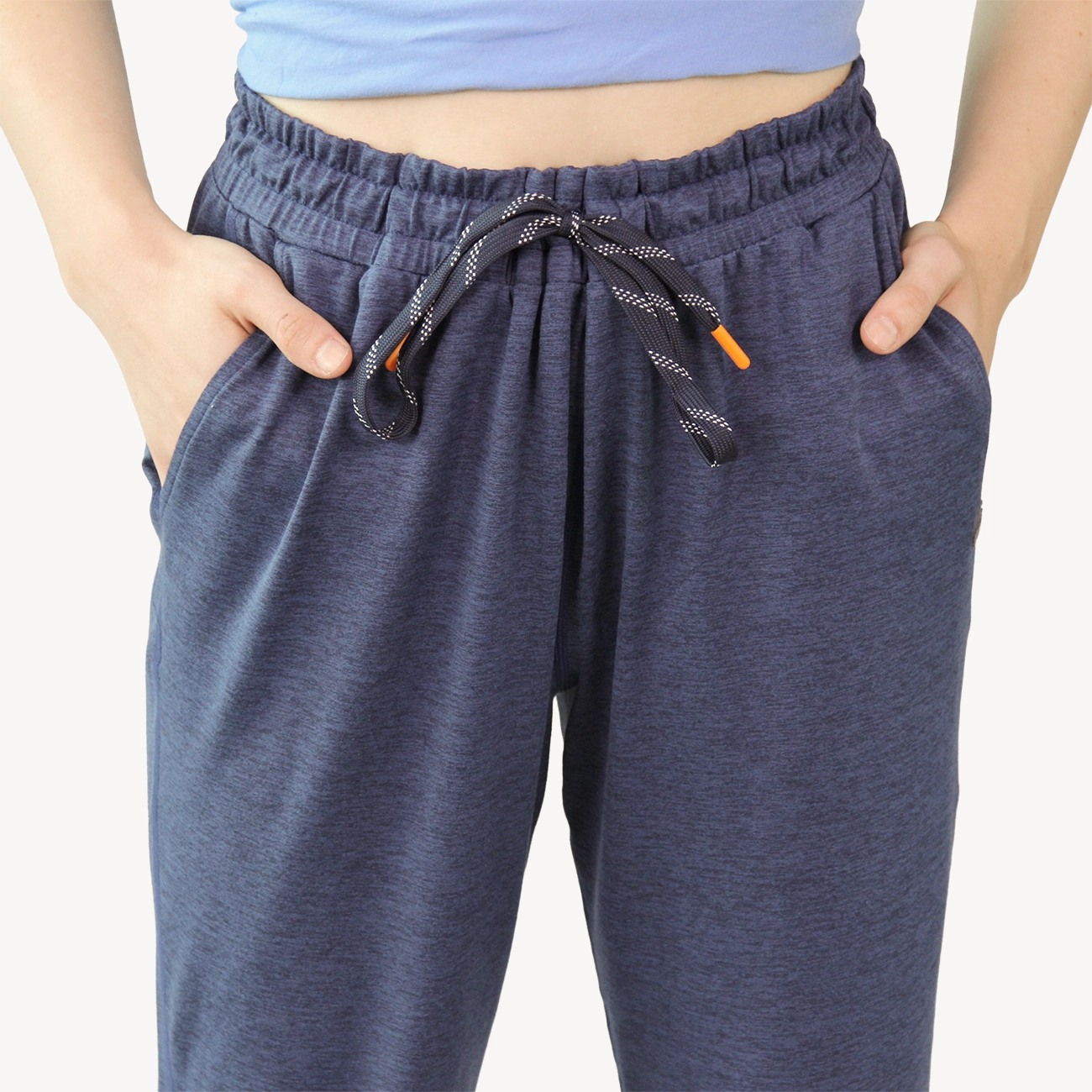 A woman wearing dark heather navy Hari Mari joggers with side pockets, paired with a blue top, shown from the waist down against a light gray studio background.