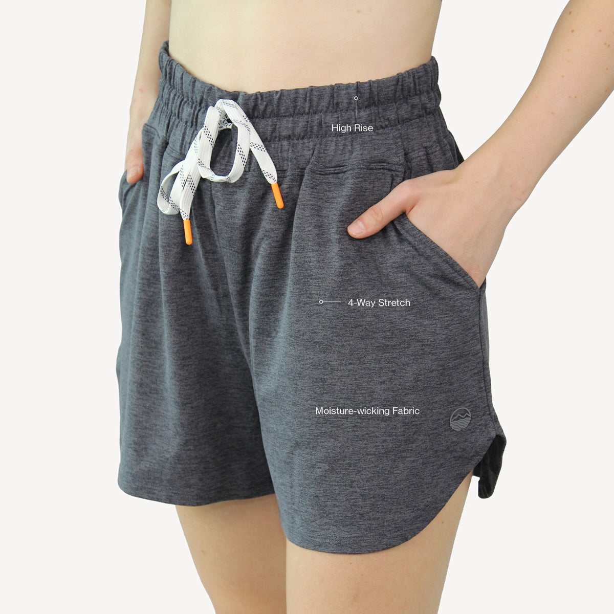 A person wearing dark heather gray athletic shorts with a white drawstring and orange tips, shown from the waist to mid-thigh against a light gray studio background. The shorts have side pockets and printed text labels reading 'High Rise,' '4-Way Stretch,' and 'Moisture-wicking Fabric.
