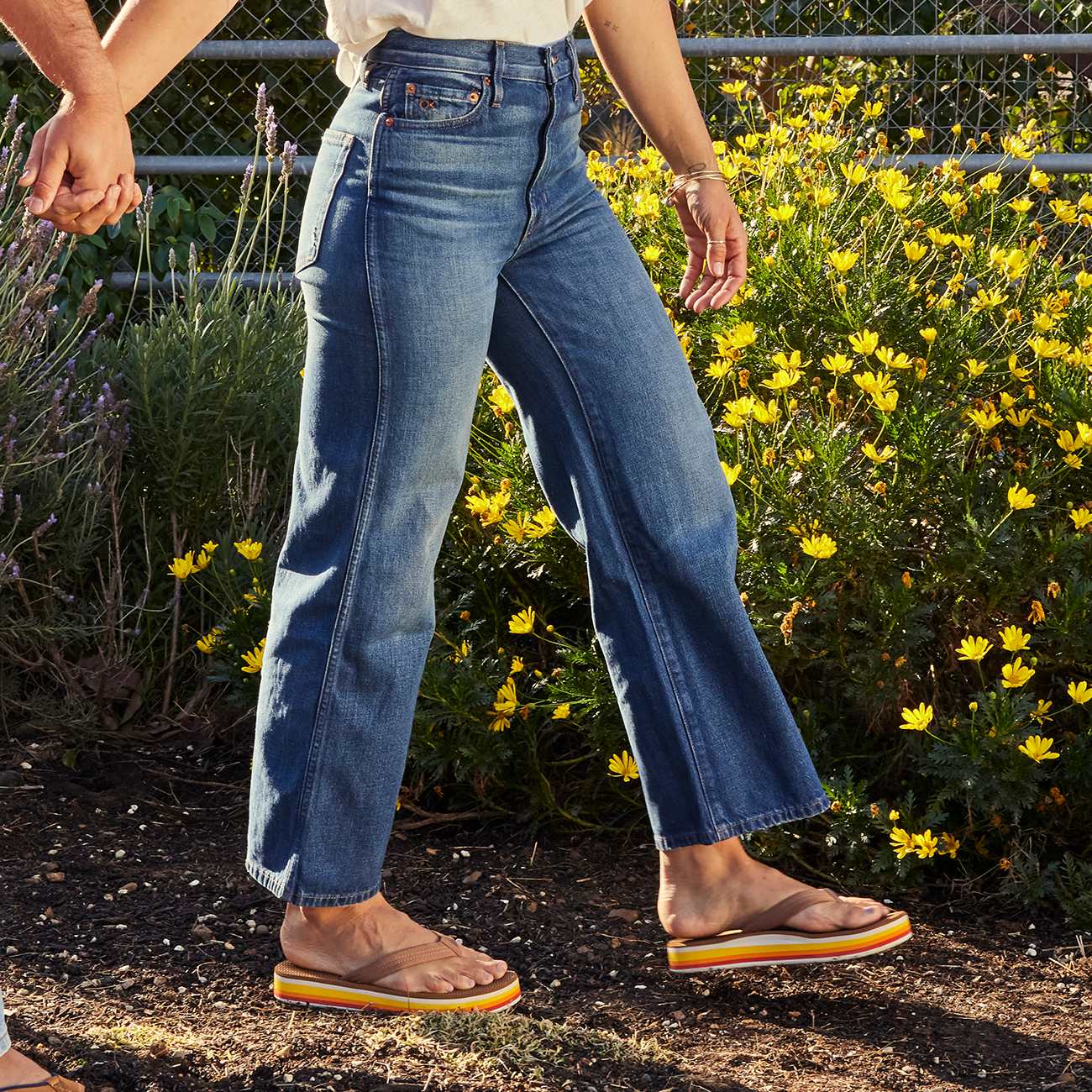 cropped photo of a woman's legs wearing jeans and brown platform sandals