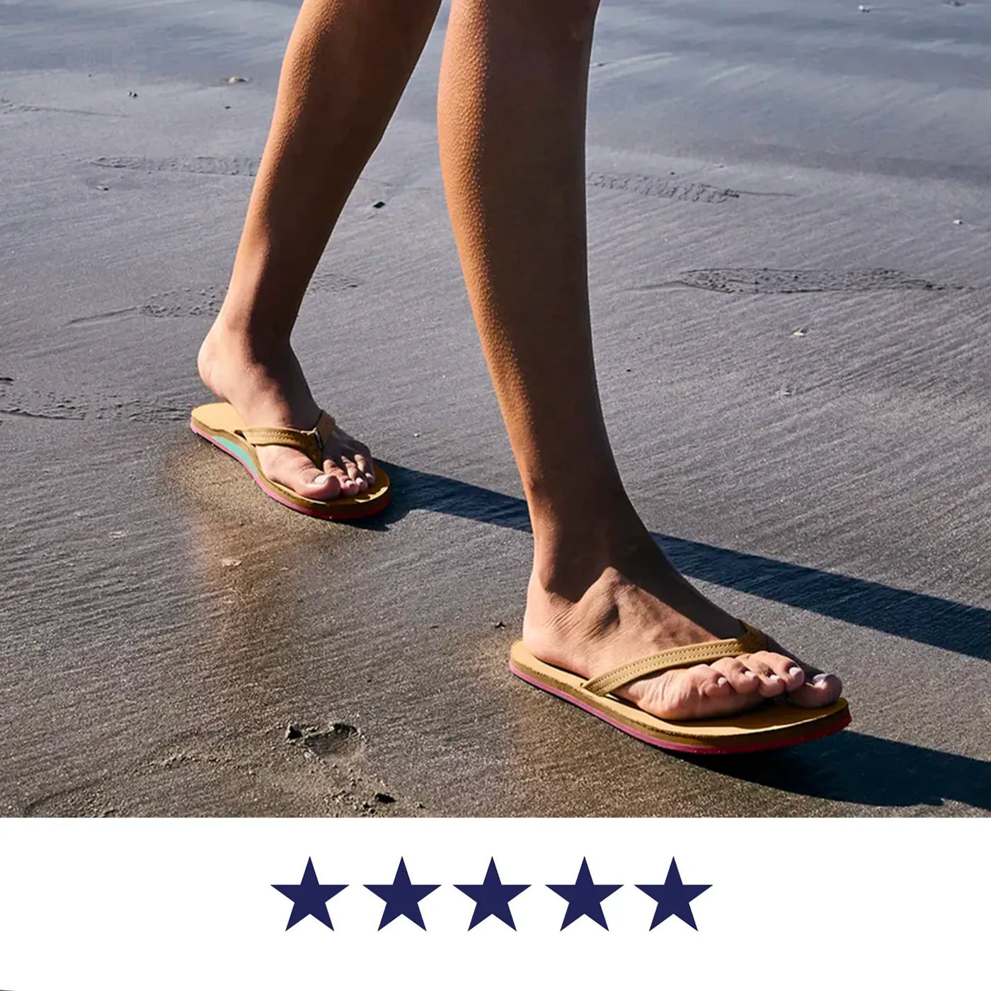 A woman walking on a sandy beach wearing tan leather women's flip-flops with a five-star graphic overlay at the bottom.