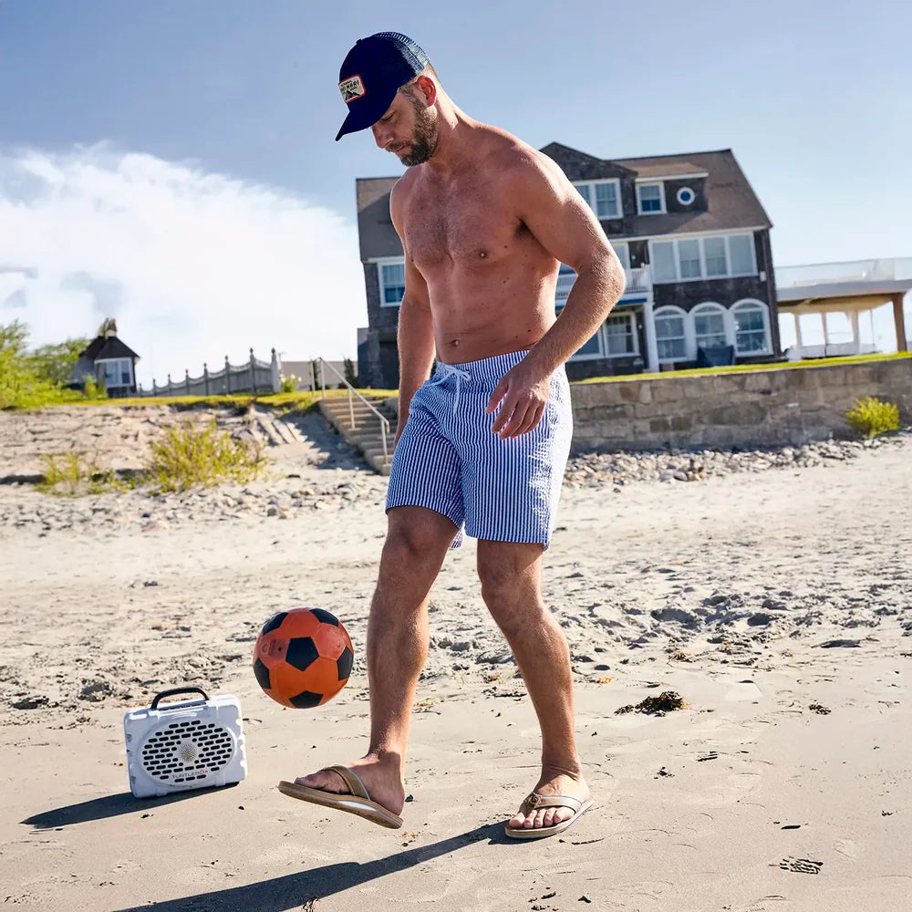 man playing soccer on a beach wearing swim trunks and Hari Mari flip flops