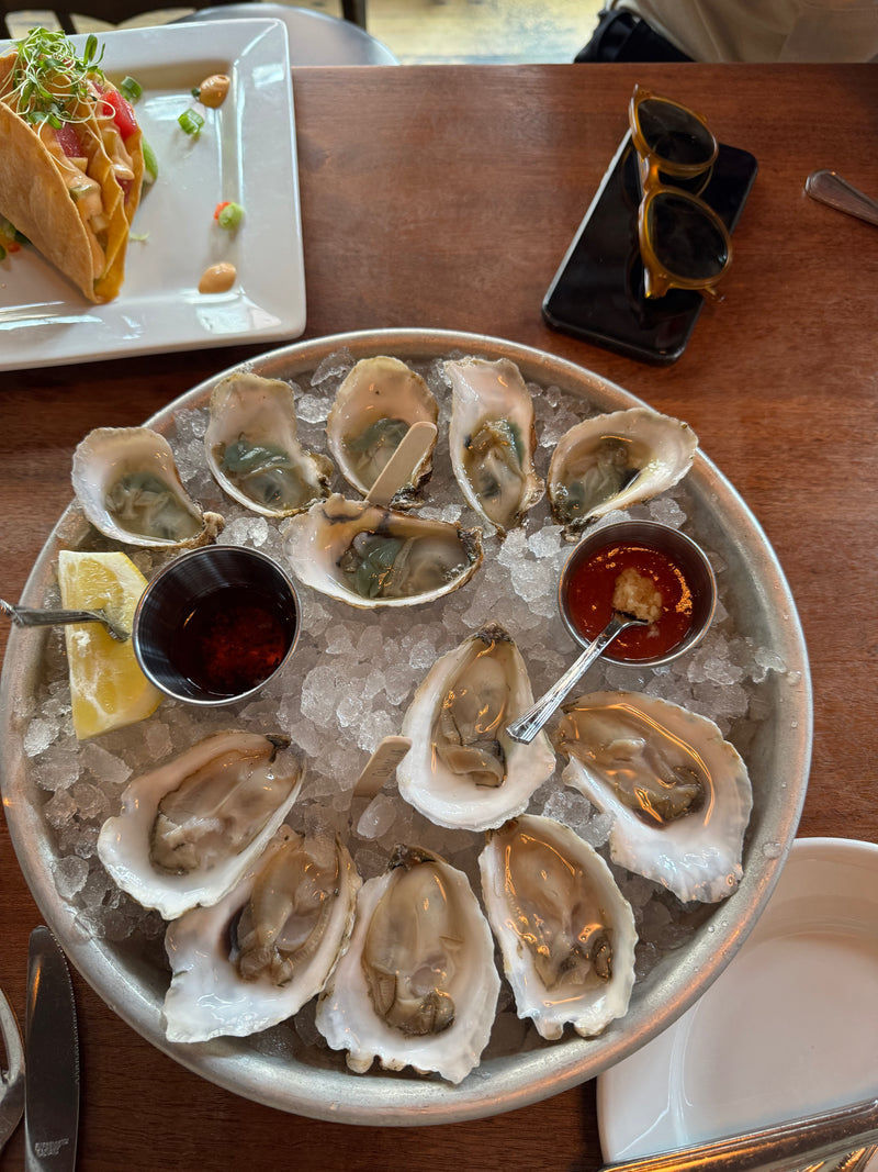 Platter of raw oysters on ice with sauces and a taco in the background in Newport, RI