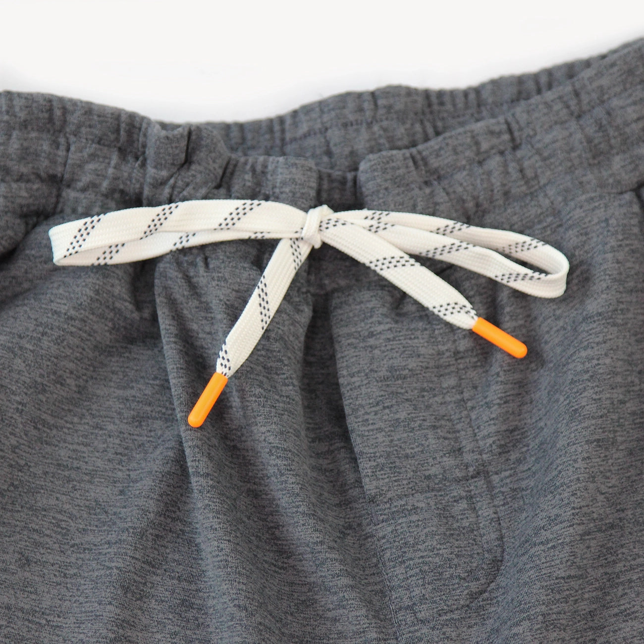 Close-up of dark heather gray drawstring shorts for men from Hari Mari showing the elastic waistband and white drawstring with black dotted pattern and orange tips.