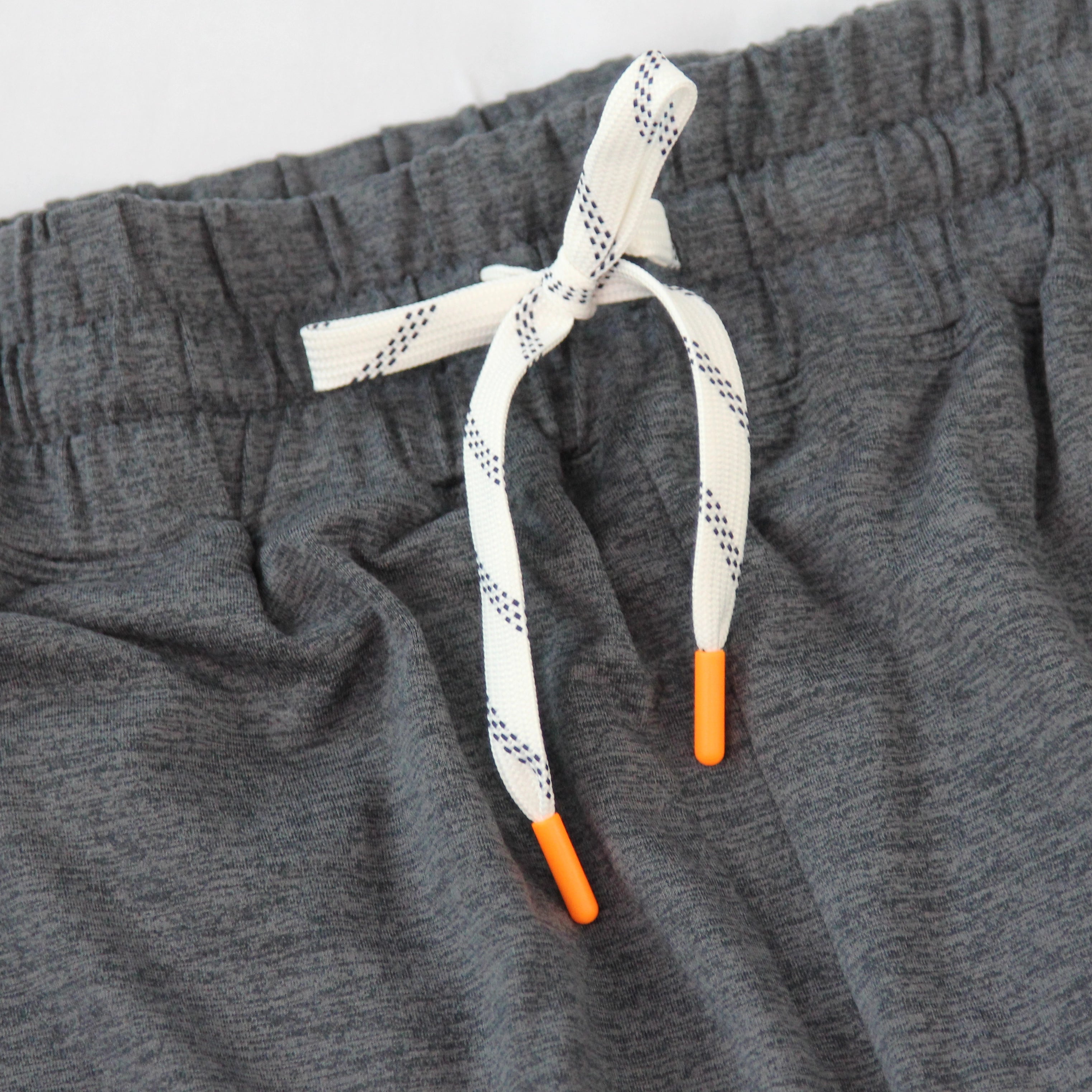 Close-up of Hari Mari heather gray shorts with a white drawstring featuring a black dotted pattern and bright orange tip accents.