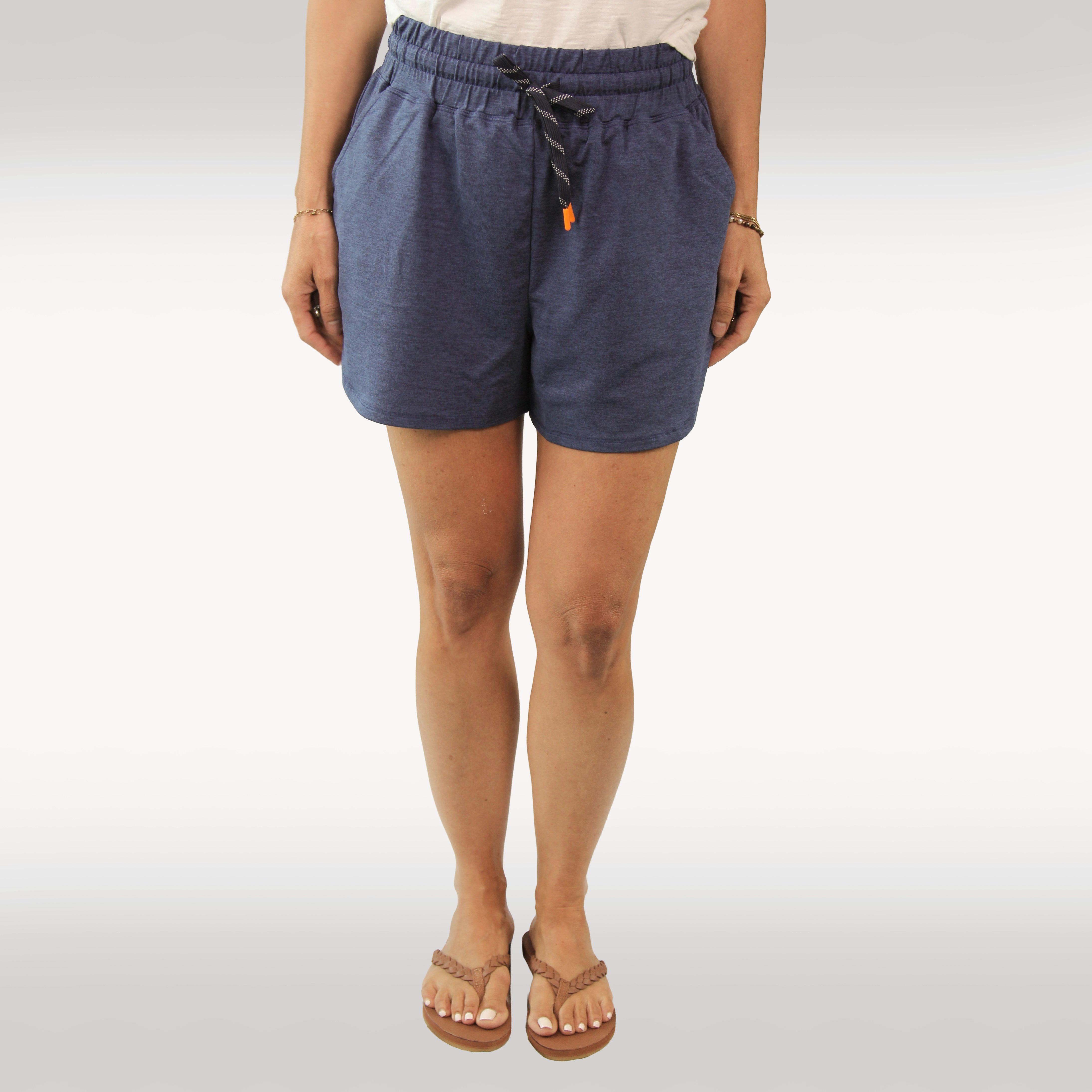 A person wearing dark heather gray drawstring shorts with side pockets, paired with tan Hari Mari flip-flops and a black top, shown from the waist down against a light gray studio background.