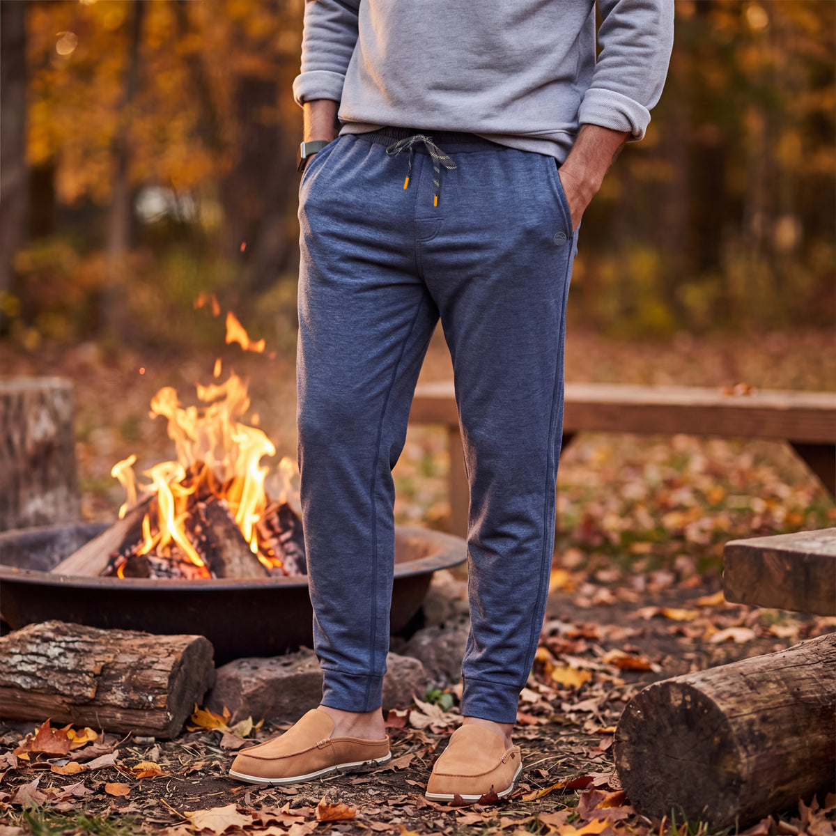 Man standing in front of a firepit wearing Hari Mari joggers and tan slippers