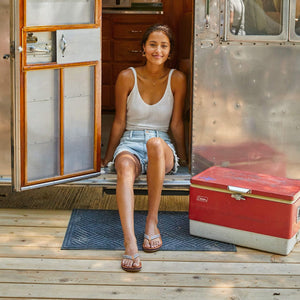woman sitting in vintage camper wearing flip flops